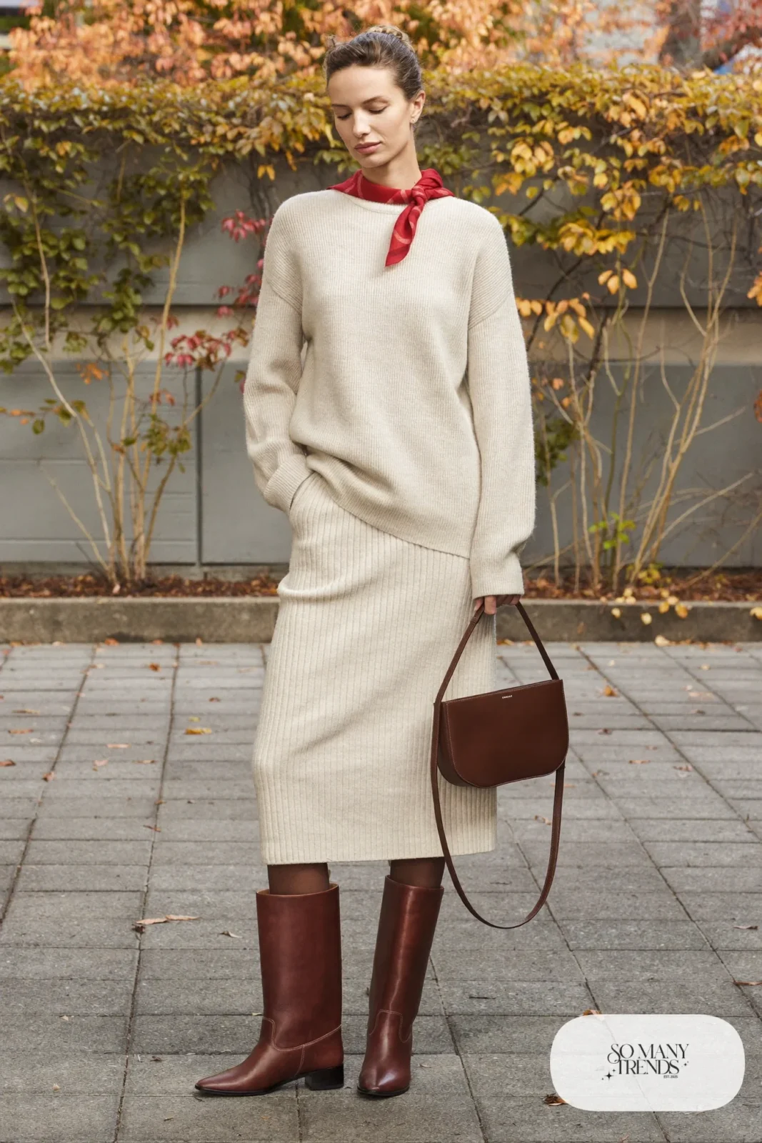 Woman in oatmeal ribbed knit sweater and midi skirt, brown boots and red scarf, outfit 13