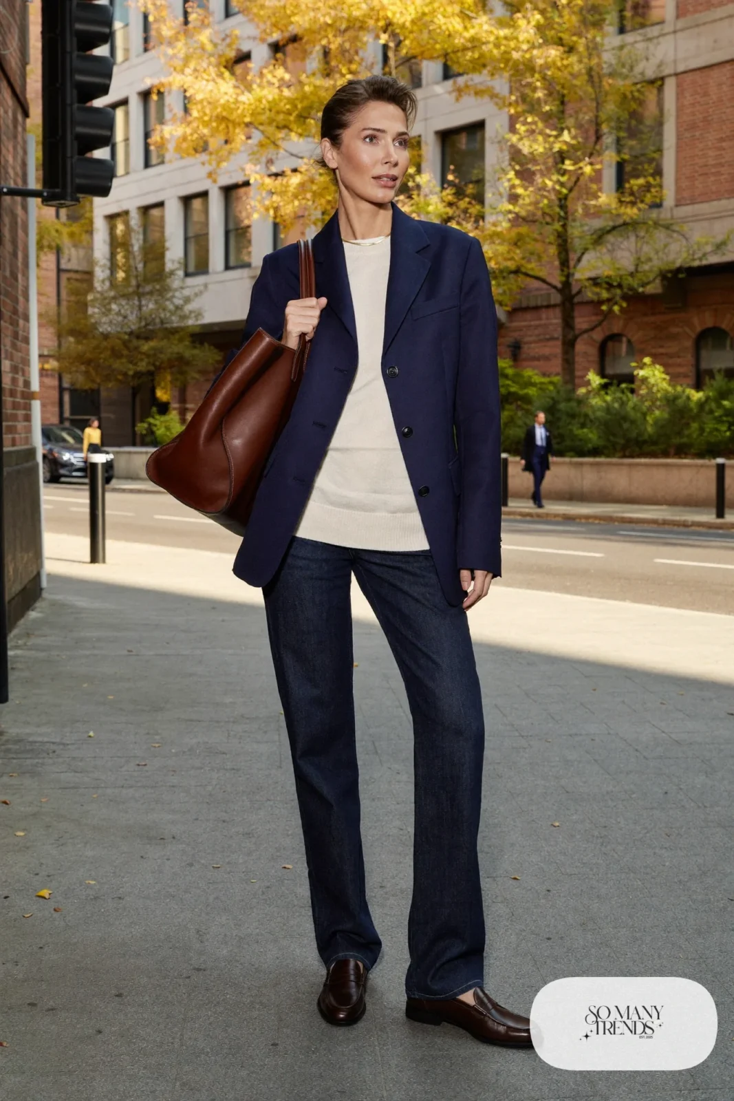 Woman in navy blazer, cream sweater, straight jeans, brown loafers and a chocolate leather tote, outfit 18