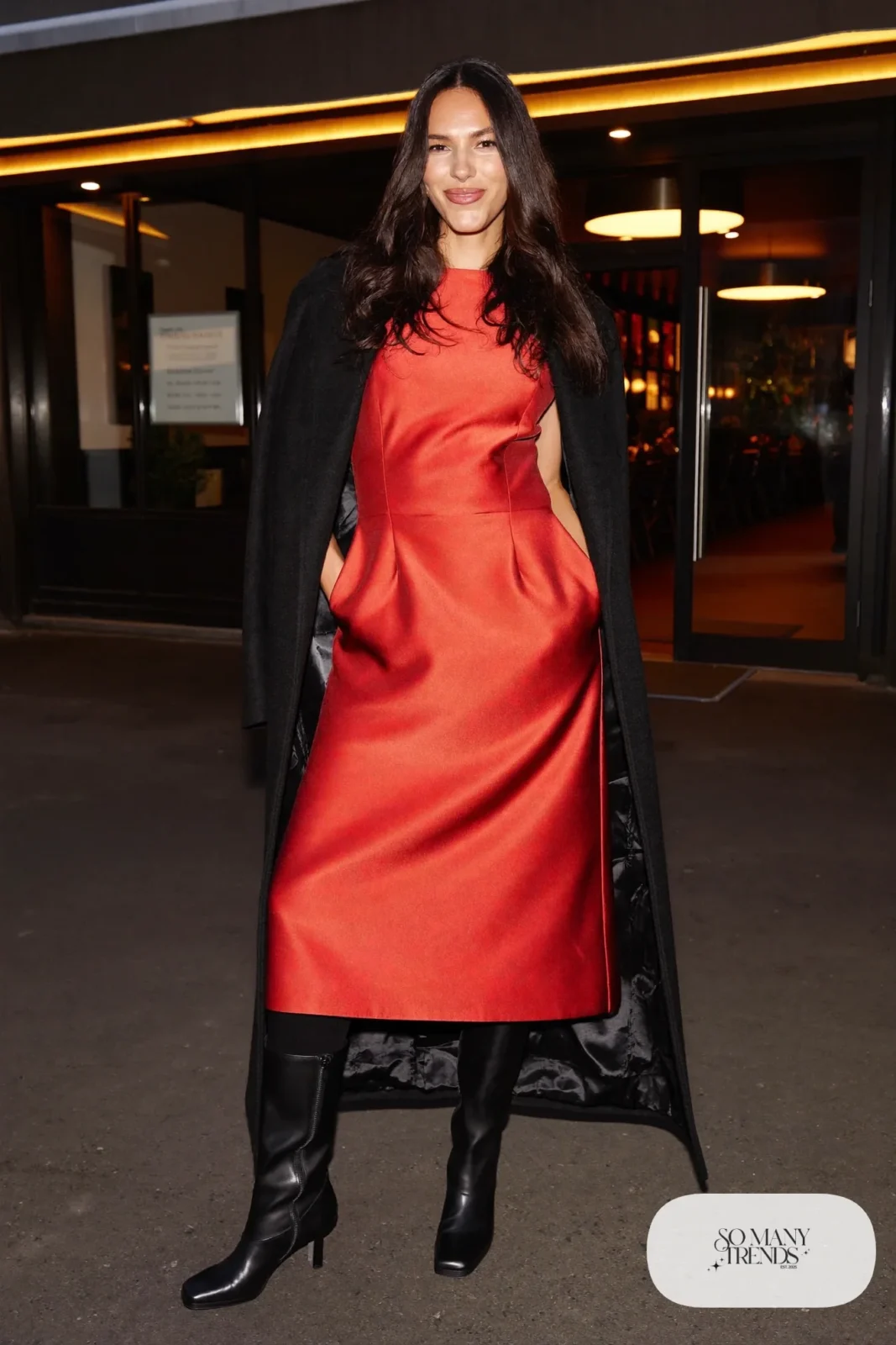 Woman in red satin midi dress, black coat, black tights and black boots, outfit 23