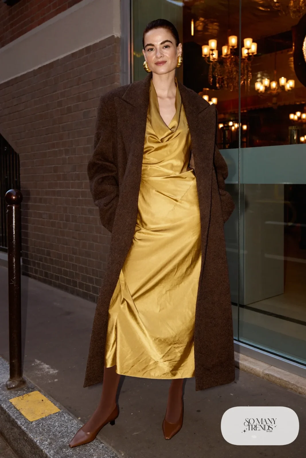 Woman in a mustard satin midi dress under a long espresso coat with brown tights and closed pumps, photo 11