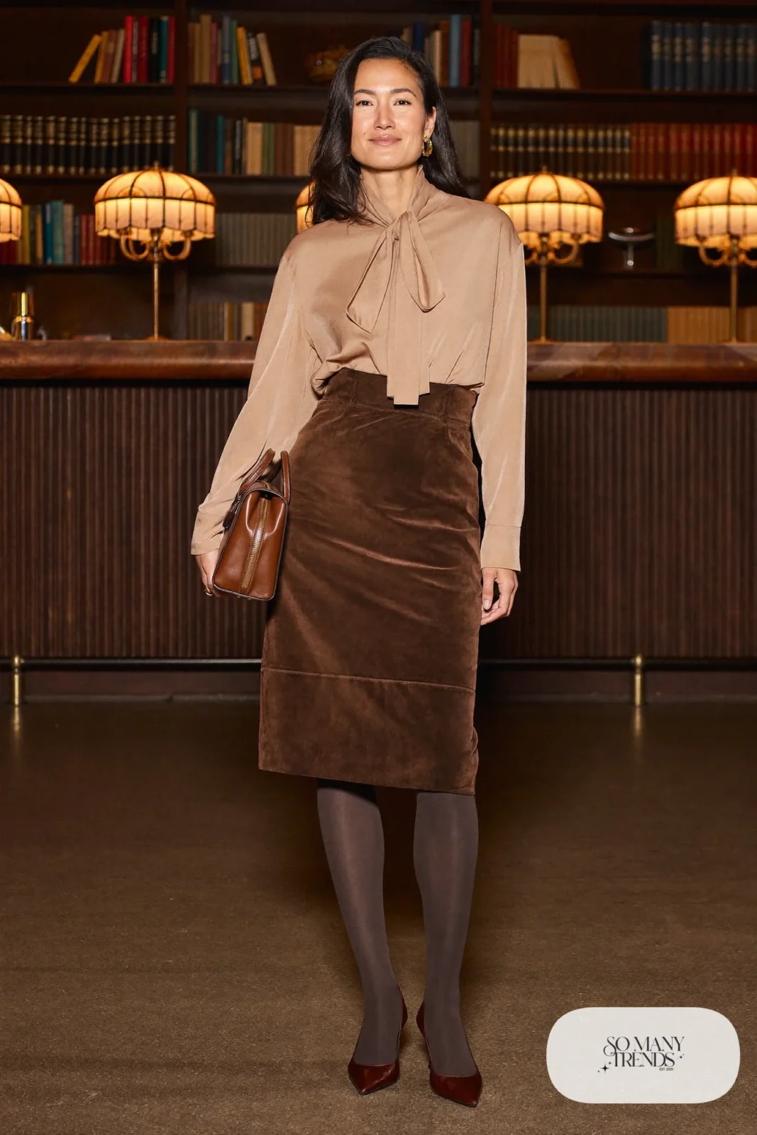 Woman in an espresso faux suede midi skirt with an oatmeal silk bow blouse, brown tights and pointed pumps, photo 18