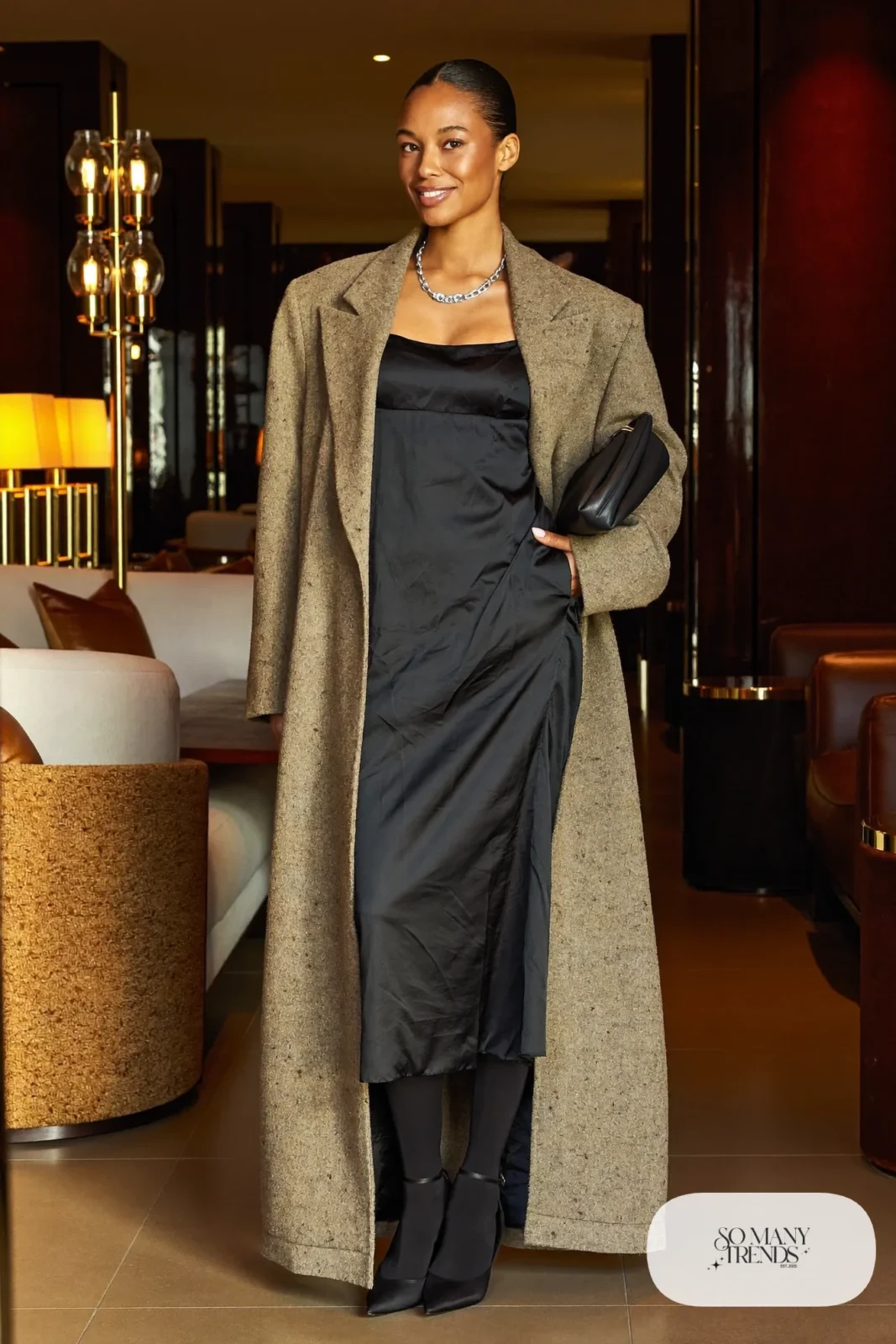 Woman in an oversized oatmeal blazer over a black satin cami dress with sheer tights and black pumps, photo 21
