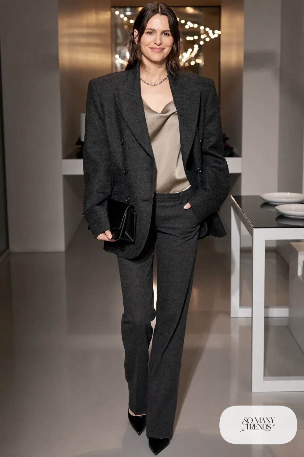 Woman in a charcoal blazer and straight pants with an oatmeal satin camisole and black pointed heels, photo 5