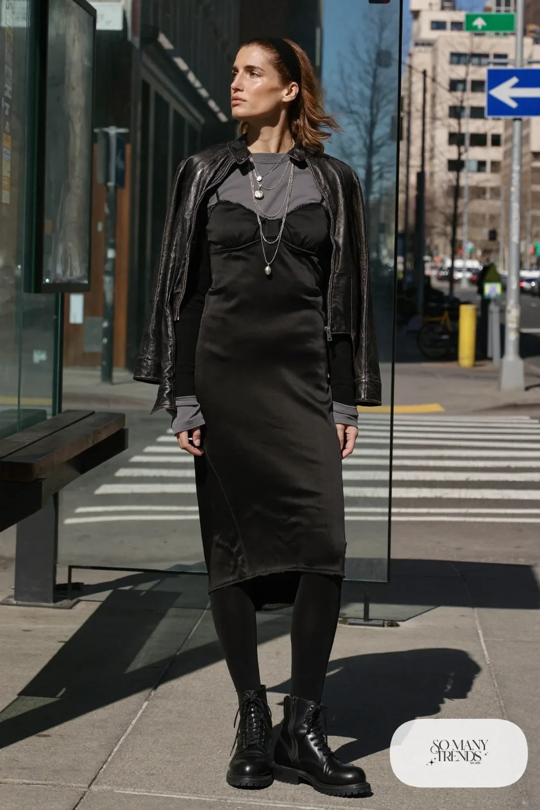 Woman in a black midi slip dress over a band tee, cropped leather jacket, thick black tights and combat boots, outfit 14