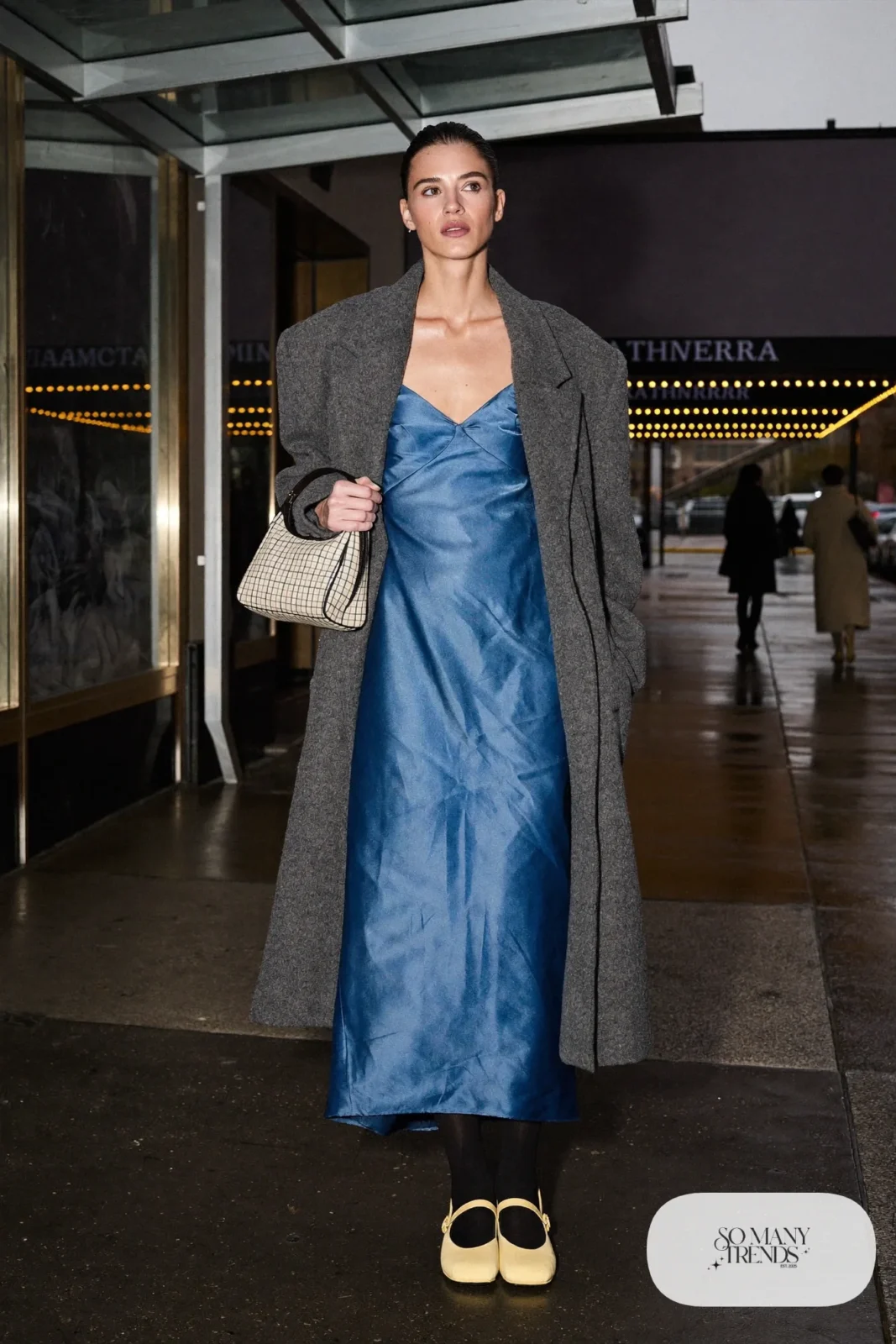 Look 5: cobalt blue satin slip dress with lace trim, black opaque tights, yellow Mary Jane shoes and a checked bucket bag under a long gray wool coat