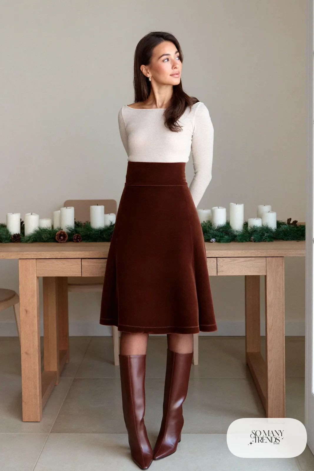 Woman in a brown velvet midi skirt, fitted cream knit, sheer tights and tall brown boots in a dining room, outfit 7