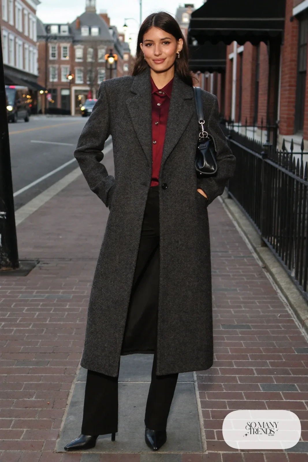 Woman in a burgundy silk-feel blouse, black blazer, black pants, black heeled boots and a charcoal coat in Georgetown, outfit 24