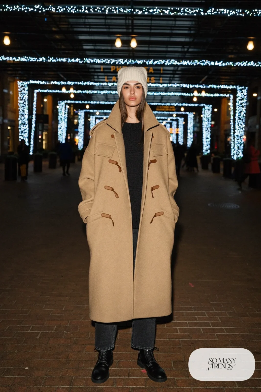 Camel duffle coat with toggles over black fine-knit sweater, dark straight jeans and black leather boots, outfit 2