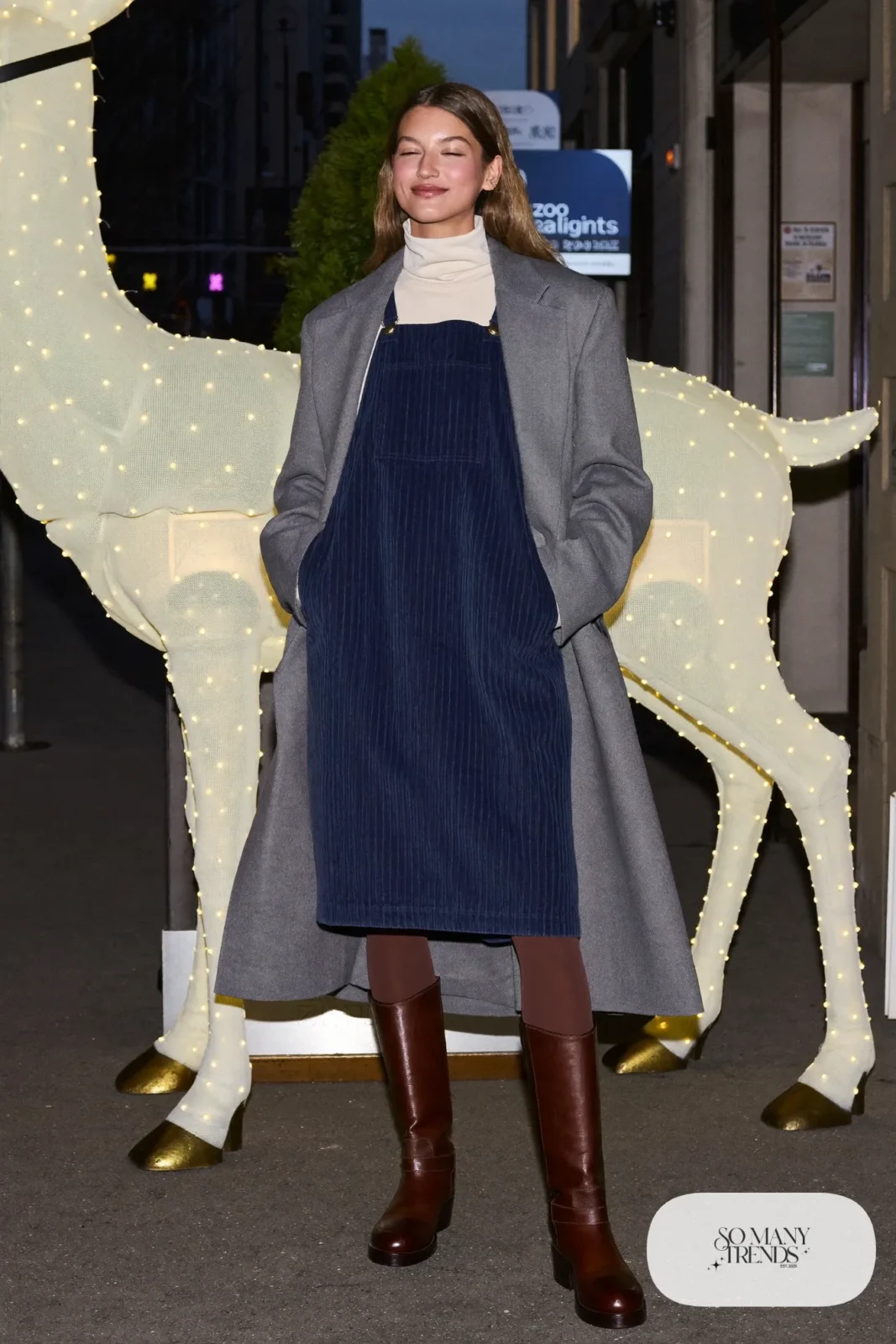 Navy corduroy pinafore dress over cream turtleneck, black tights, brown boots and a gray wool coat, outfit 11