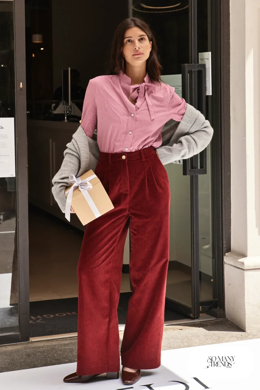 Woman in a dusty pink bow-collar blouse, burgundy wide-leg corduroy pants, gray cardigan and brown block-heel shoes, outfit 11