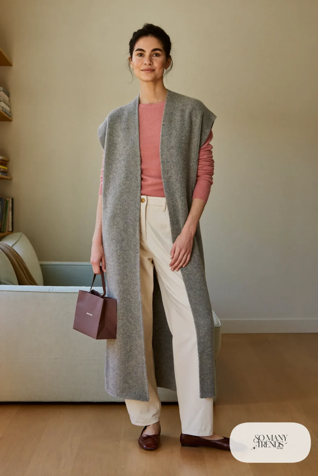 Woman in a gray knit vest over a dusty pink sweater, cream straight-leg pants and burgundy flats, outfit 12