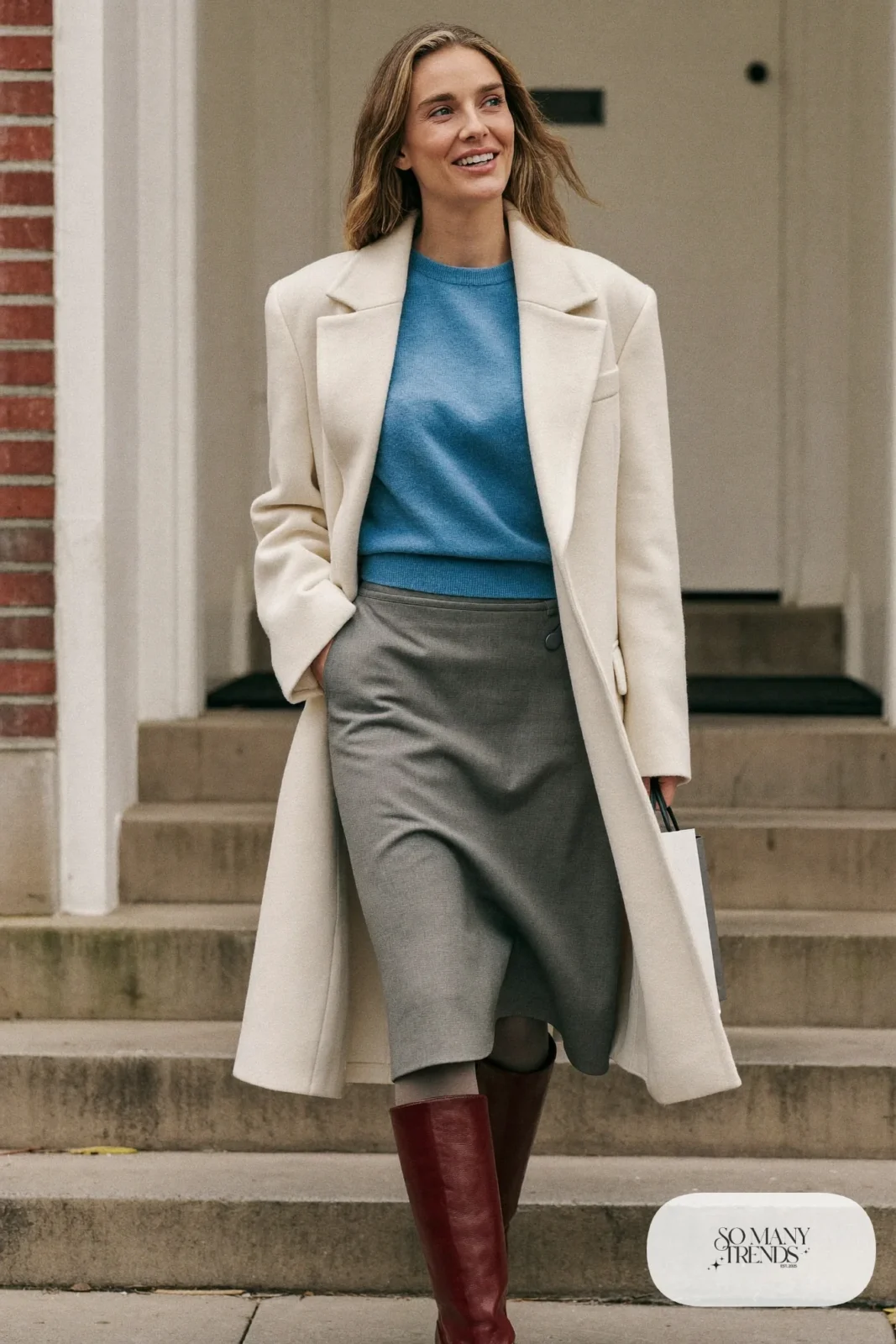 Woman in a soft blue sweater tucked into a gray midi skirt with a burgundy belt, gray tights and burgundy ankle boots, outfit 29