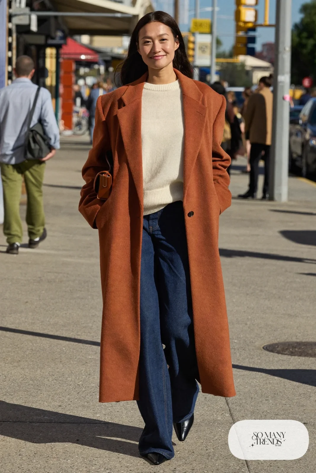 Woman in a long terracotta wool coat, cream knit, indigo wide-leg jeans and black ankle boots on the Las Vegas Strip, outfit 1
