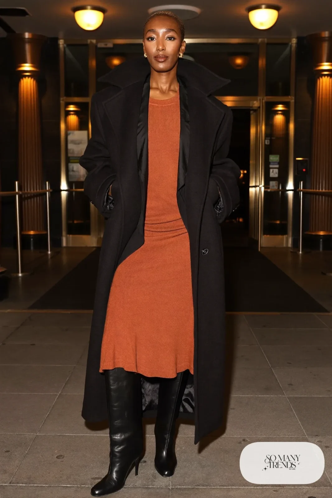 Woman in a terracotta ribbed knit midi dress, long black coat and tall black boots in Las Vegas, outfit 19