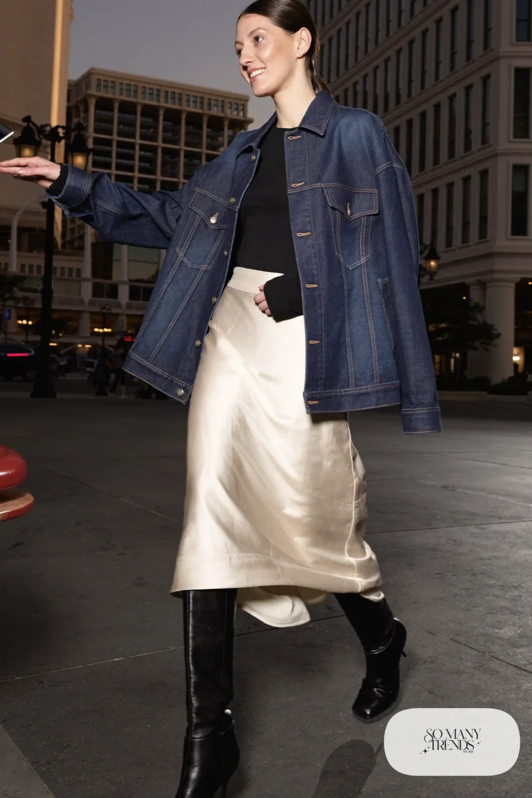 Woman in an oversized indigo denim jacket, cream satin midi skirt, black tee and pointed boots in Las Vegas, outfit 24