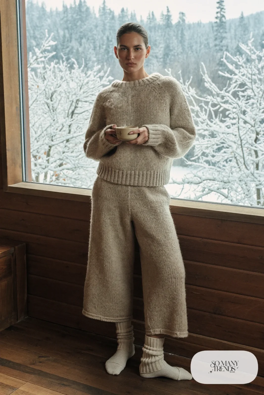 Oatmeal knit sweater and wide-leg knit pants set with thick wool socks in snow cabin, outfit 14