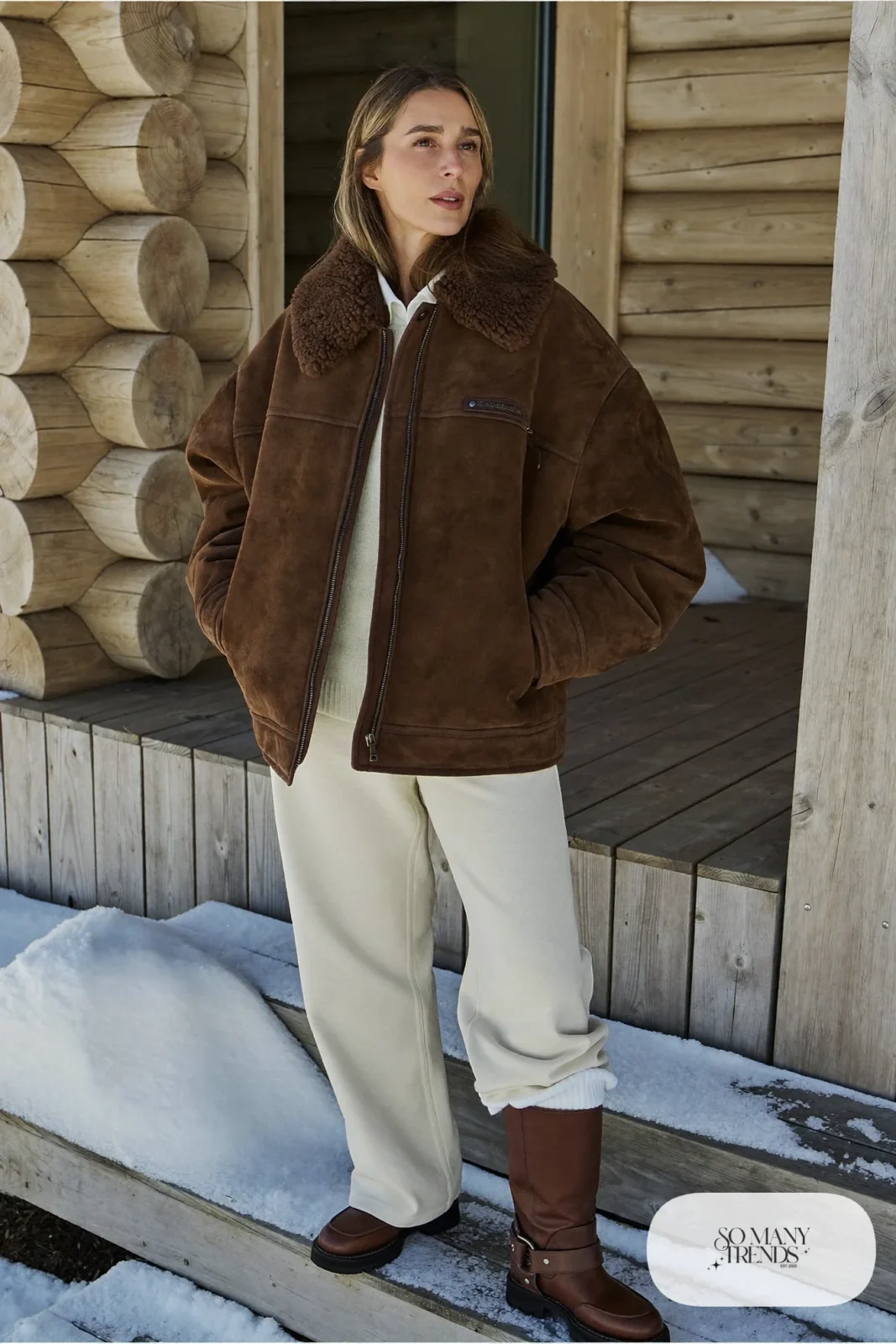Look 3: oversized chocolate shearling jacket over a cream sweater and cream straight pants with brown boots, snowy porch steps