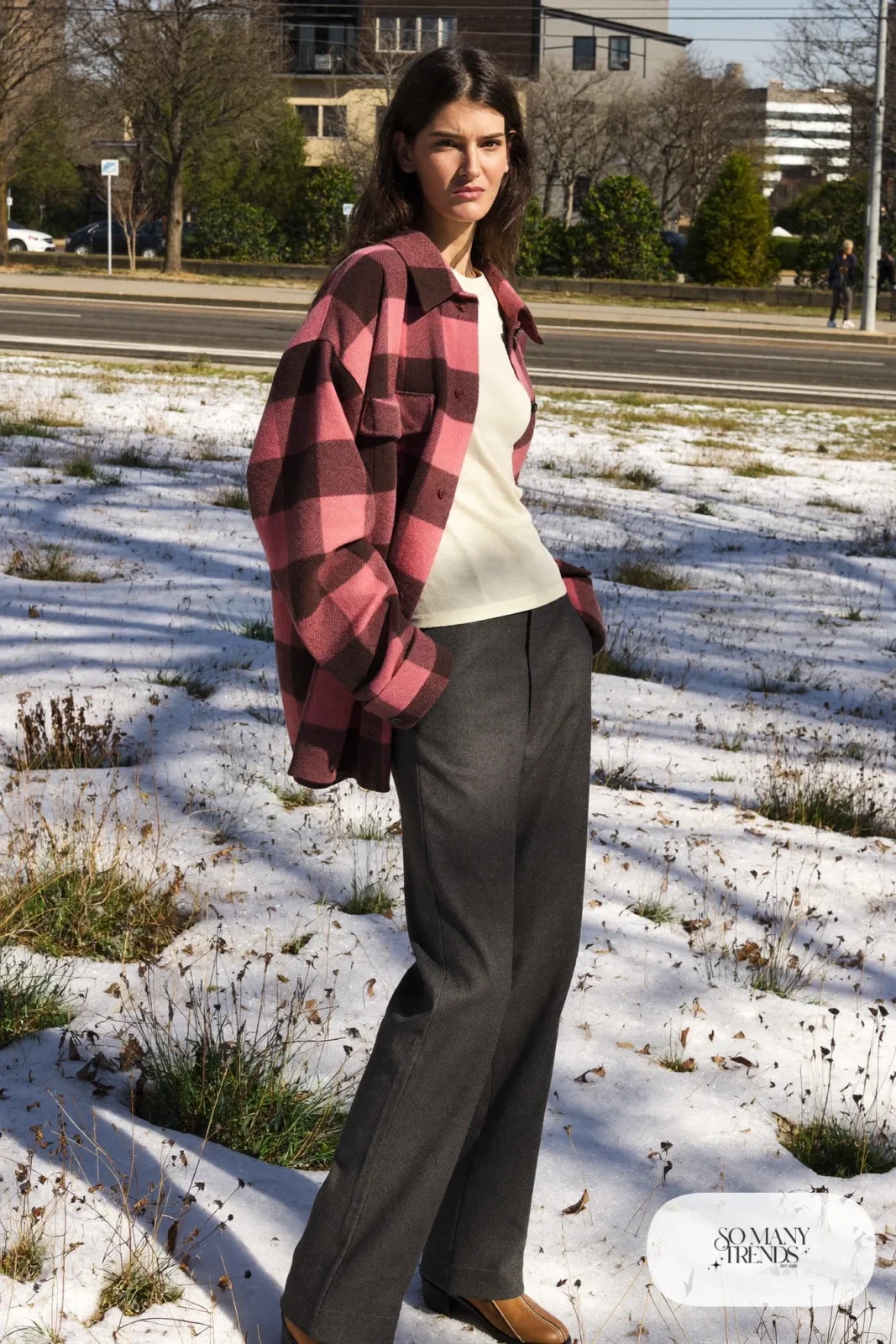 Look 11: rose and brown wool plaid overshirt over a cream thermal top with charcoal pants and brown boots, sunny snowy meadow