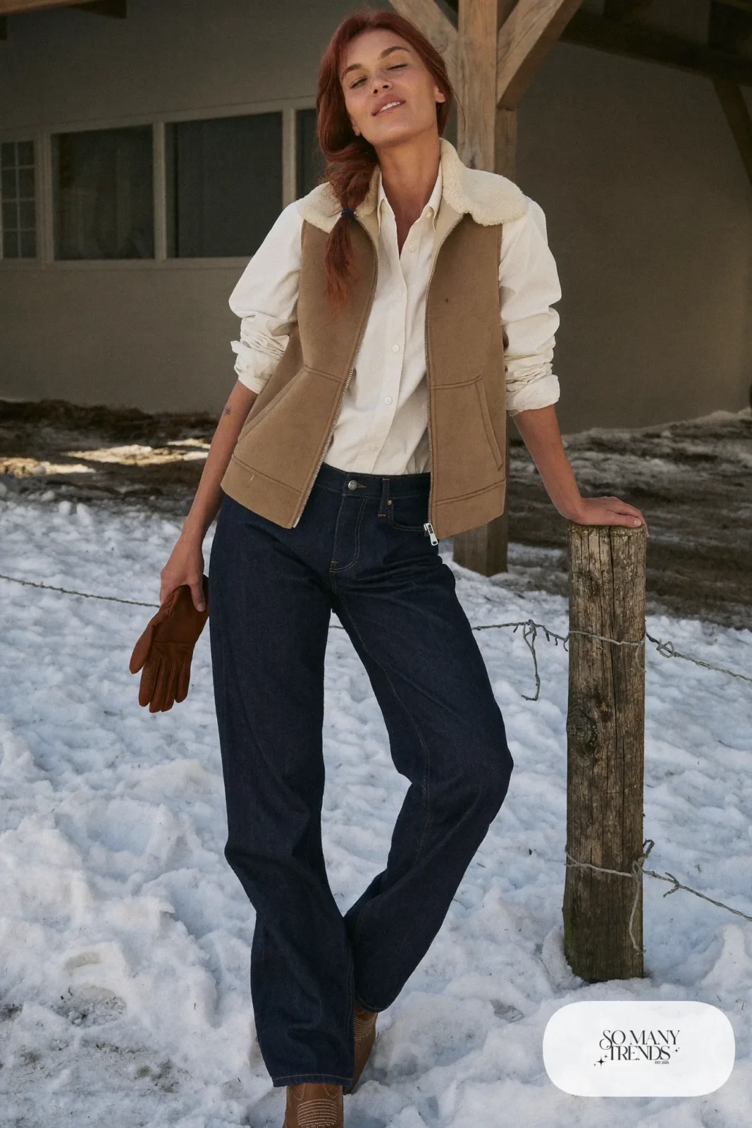 Woman in a tan shearling vest over a cream shirt with dark jeans and tan boots, outfit 6