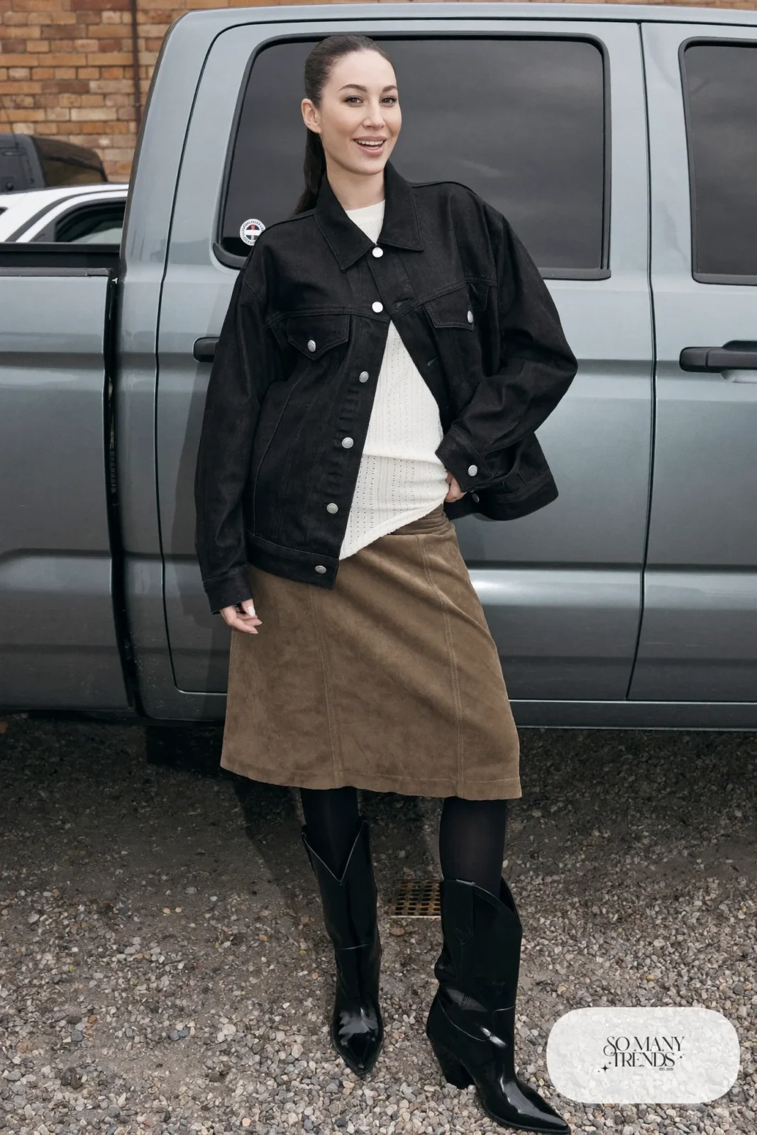 Woman in a black denim jacket, taupe suede skirt, black tights and black boots, outfit 14