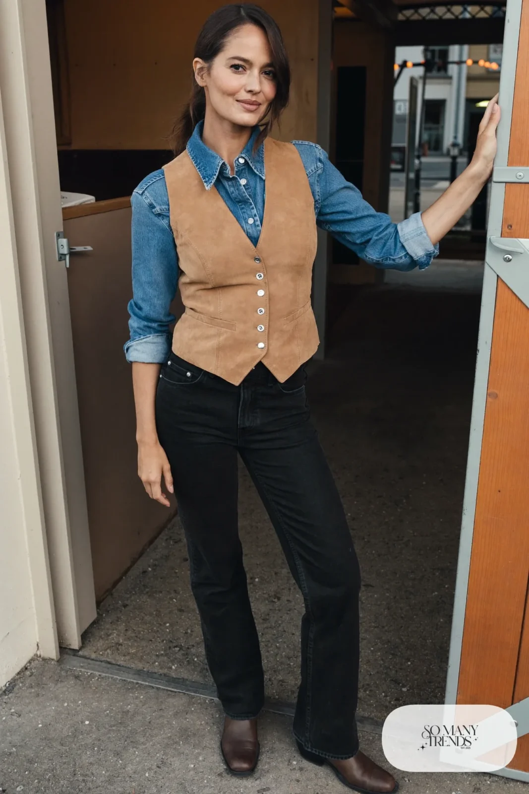 Woman in a denim western shirt, tan suede vest, black jeans and brown cowboy boots, outfit 18