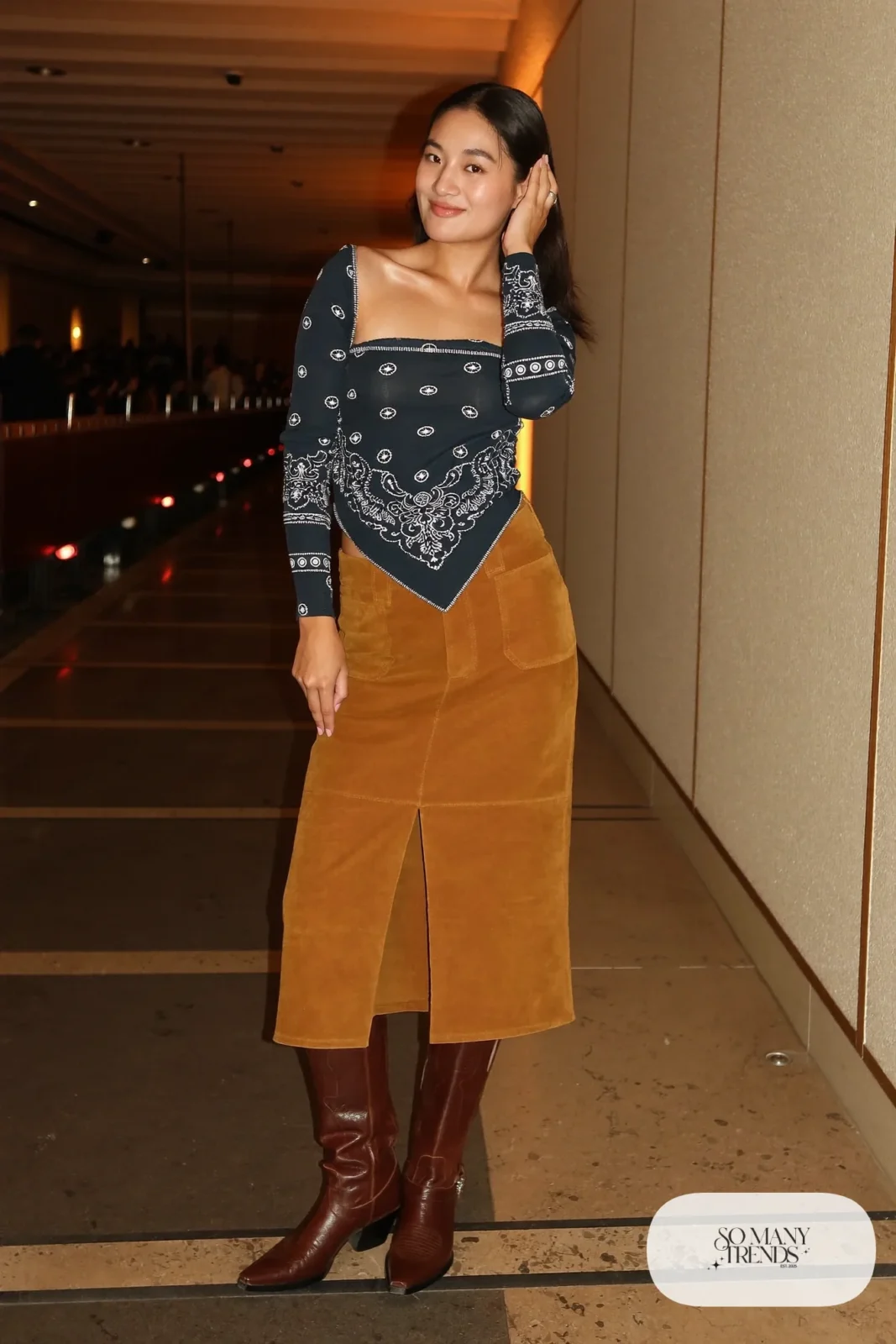 Woman in navy bandana print rhinestone top, camel midi skirt with slit and brown cowboy boots, outfit 11