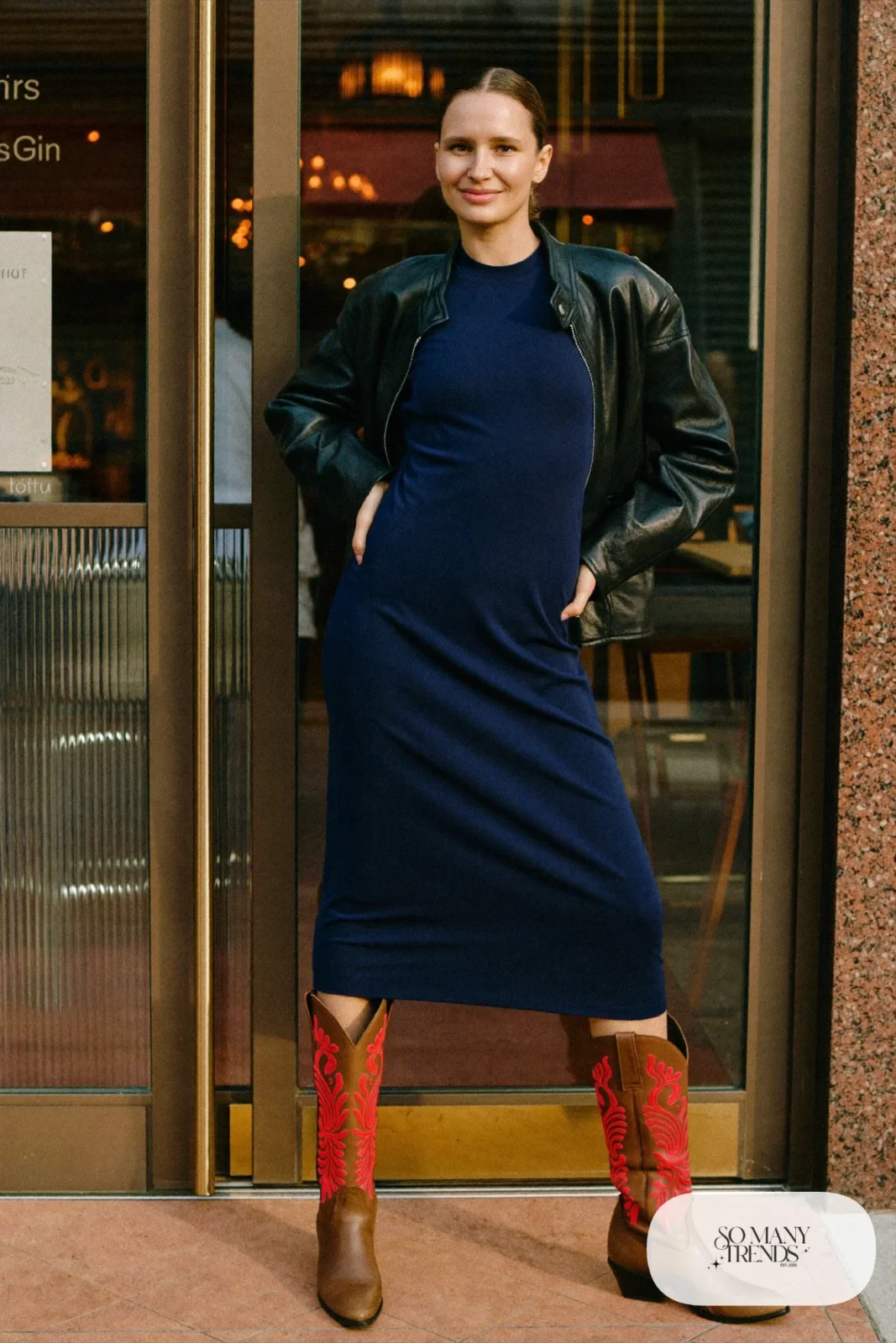 Woman in navy matte jersey midi dress, black leather jacket and embroidered cowboy boots, outfit 18