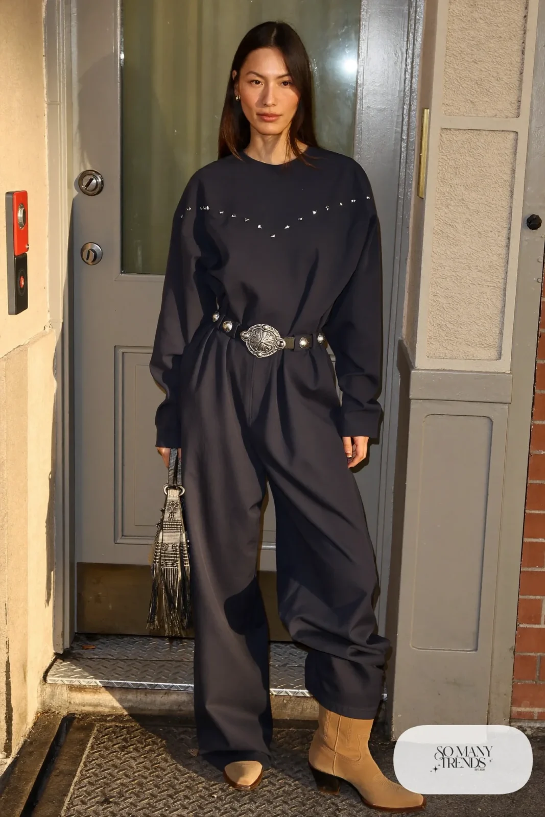 Woman in navy western yoke jumpsuit, concho belt and tan cowboy boots, outfit 23