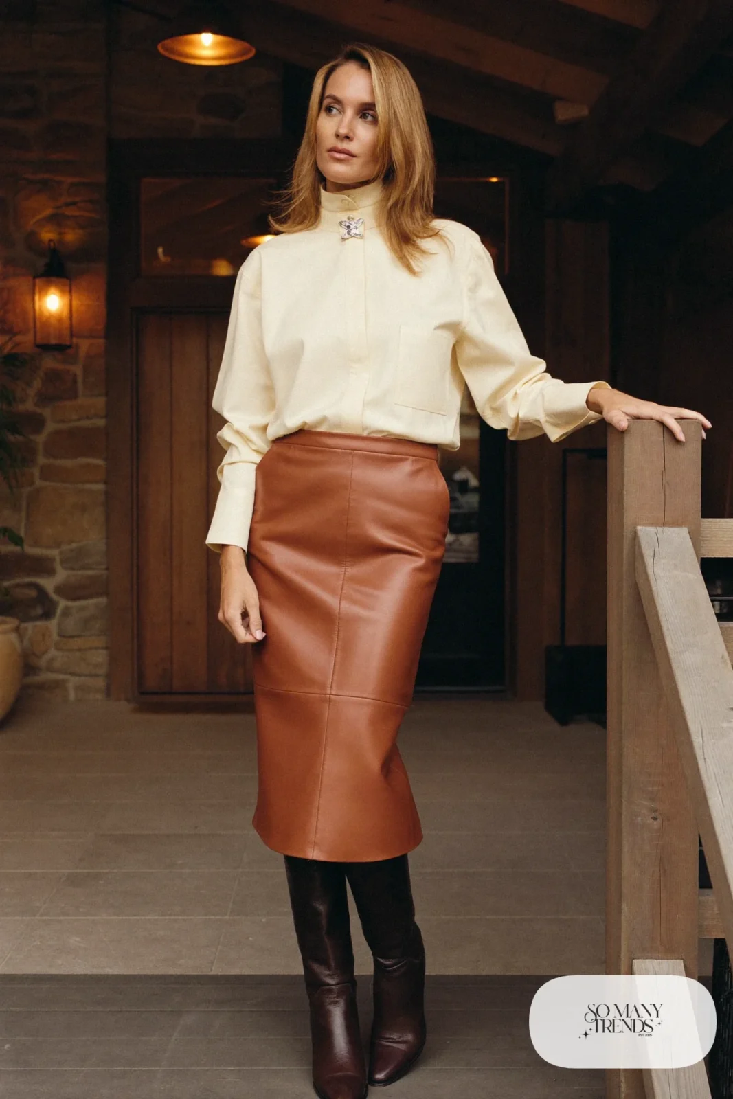 Woman in a cognac leather midi skirt with a cream high-collar blouse and tall boots, western gala outfit 7
