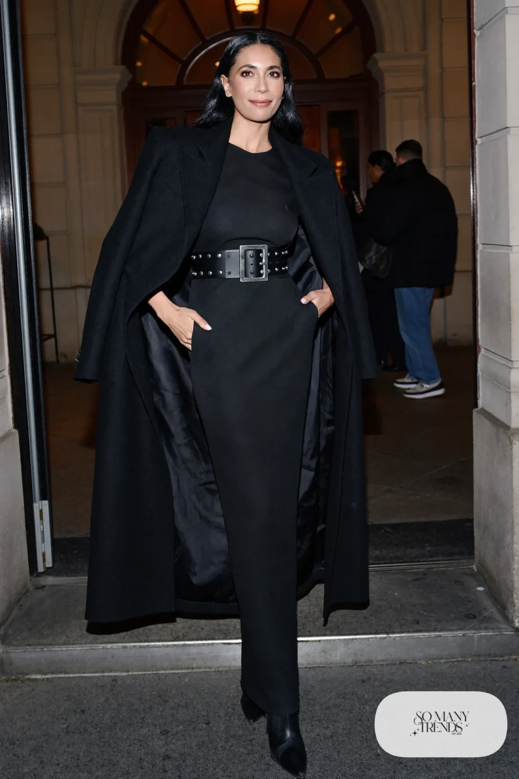 Woman in a sleek black gown with a wide studded western belt and pointed boots, western gala outfit 27