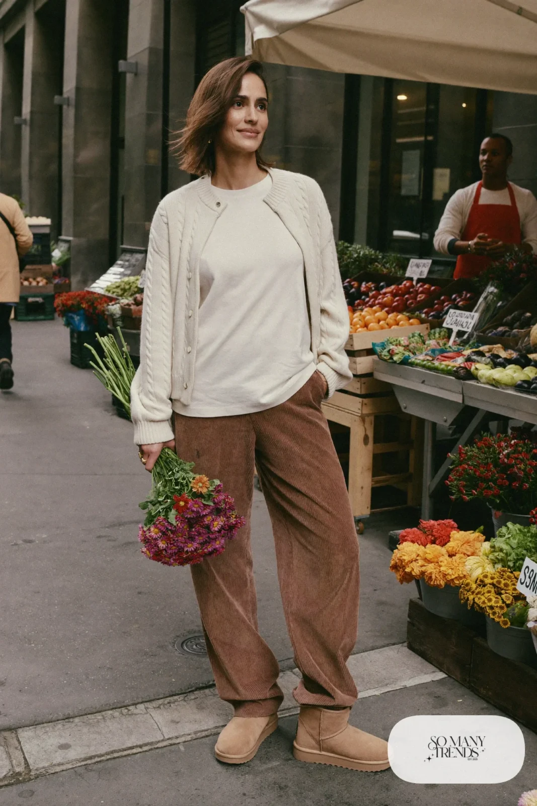 Woman in mocha corduroy straight pants, white tee, cream cardigan and sand Ugg mini boots, outfit 13
