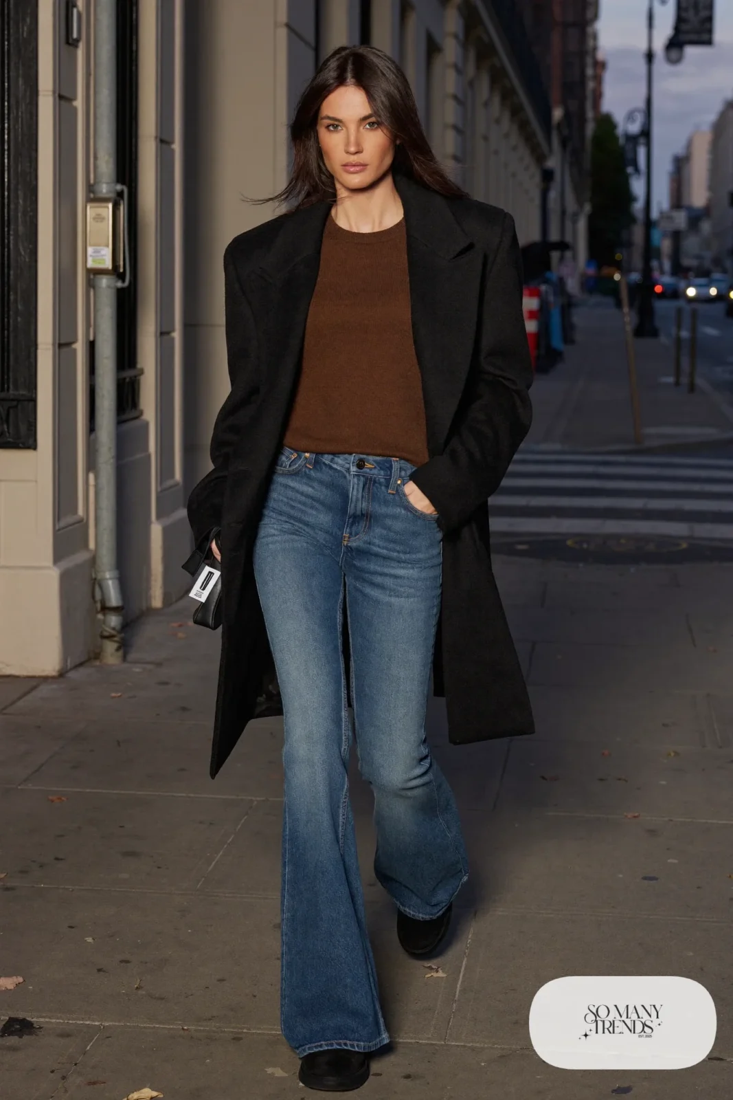 Woman in mid-wash flared jeans, fitted brown knit, short black coat and black Ugg mini boots, outfit 24