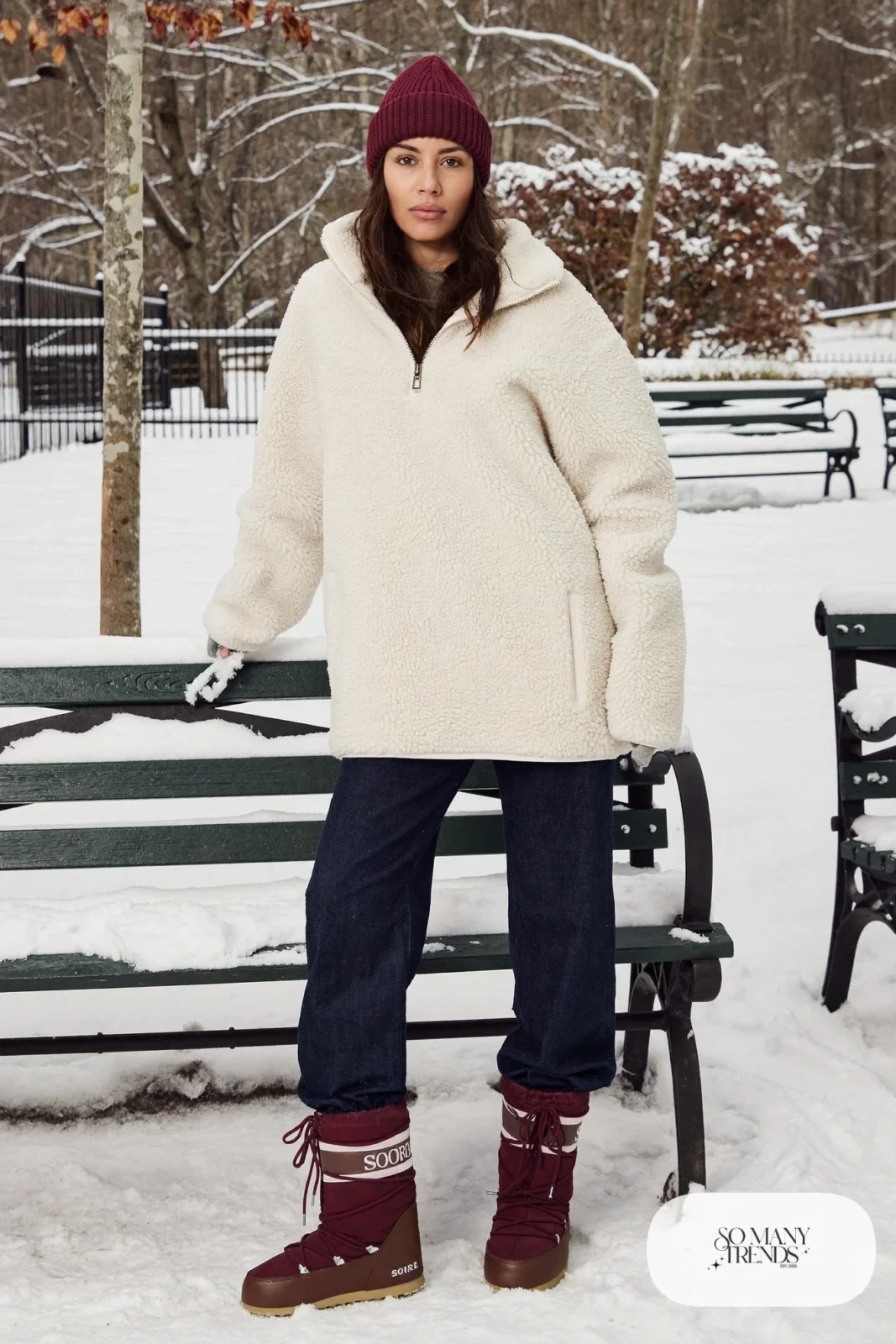 Woman in a cream sherpa pullover, burgundy beanie, dark jeans and brown Sorel boots, outfit 9