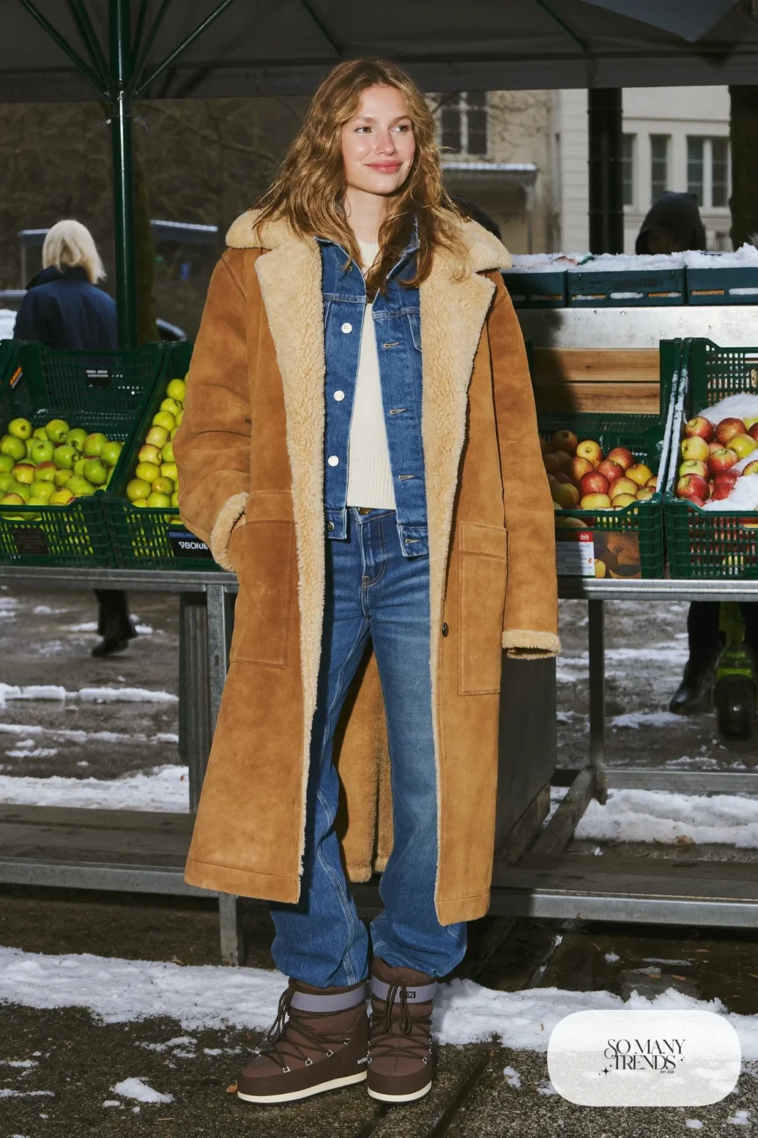 Woman in a shearling-lined coat over a denim jacket, straight jeans, cream sweater and Sorel boots, outfit 18
