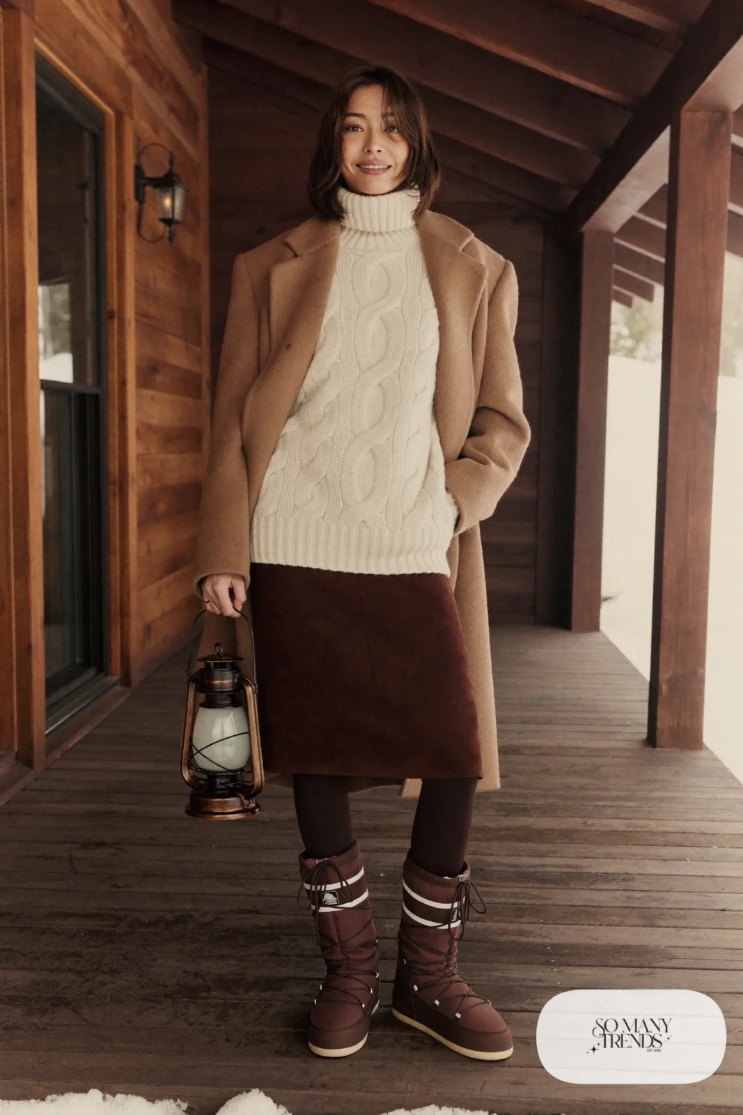 Woman in an ivory Aran sweater, chocolate midi skirt, brown tights and tall Sorel boots, outfit 22