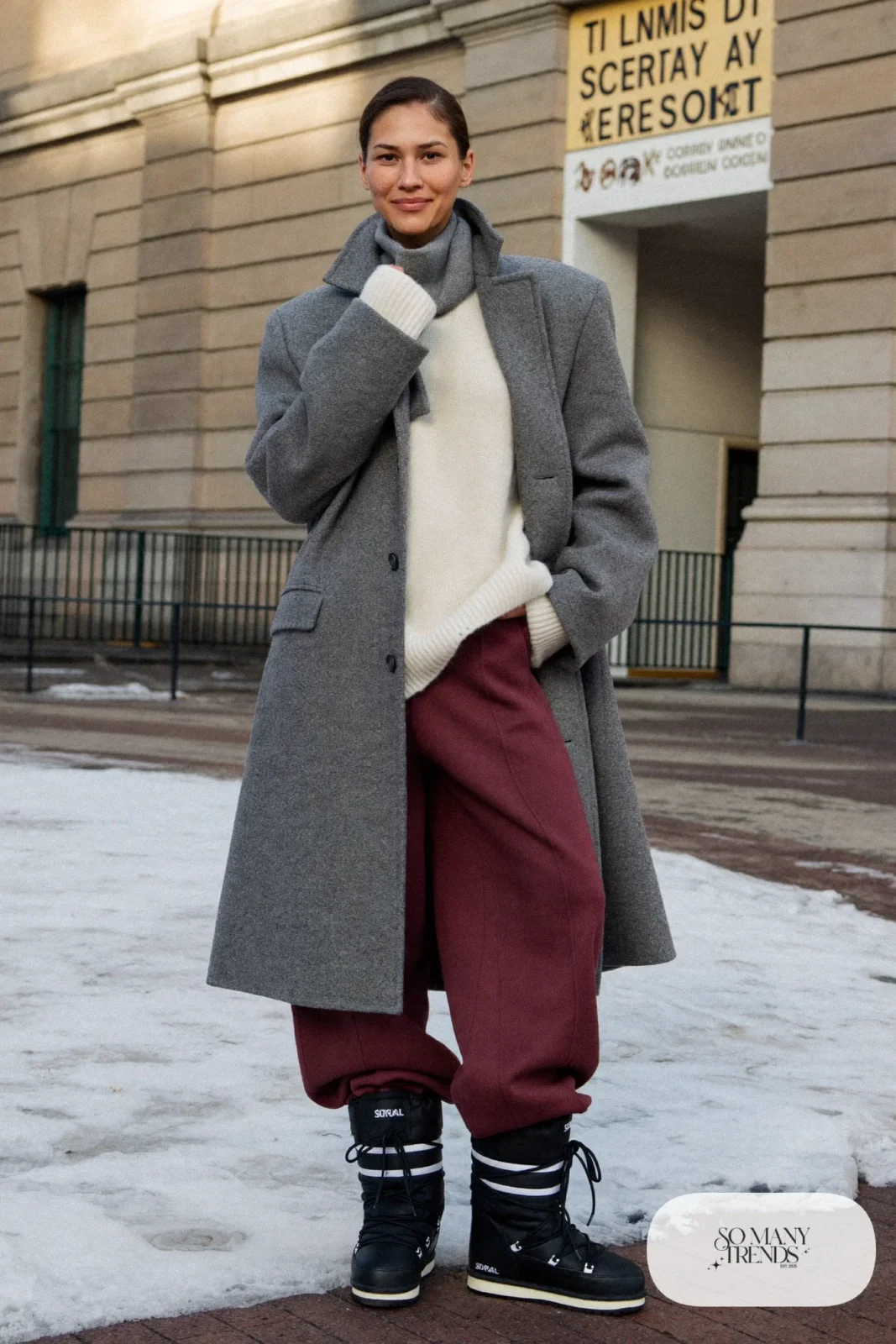 Woman in a gray overcoat, burgundy wool pants, cream sweater and black Sorel boots, outfit 23