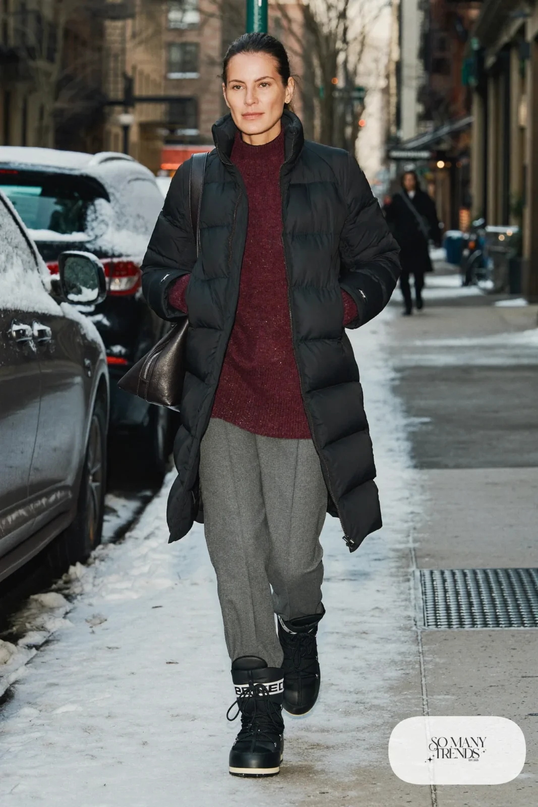 Woman in a black puffer coat, burgundy knit sweater, gray wool pants and black Sorel boots, outfit 26