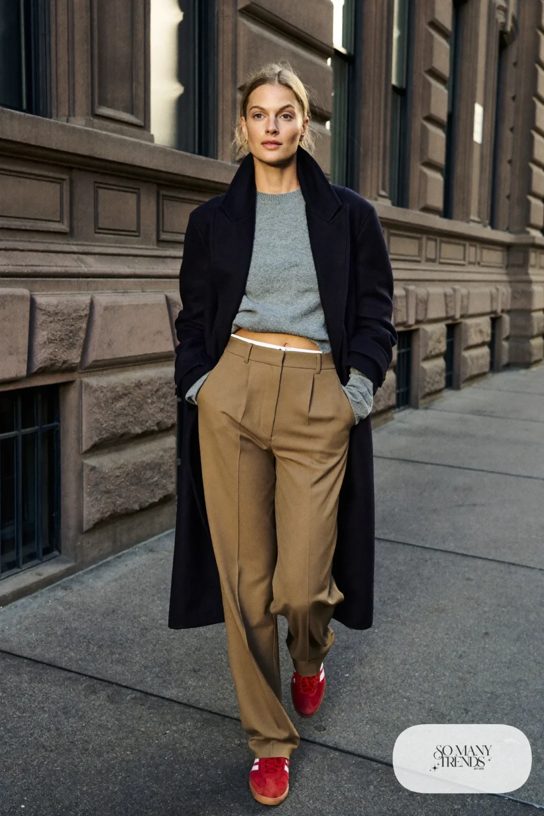 Woman in camel pleated pants, gray fine-knit sweater, navy topcoat and red Adidas Gazelle sneakers, outfit 12