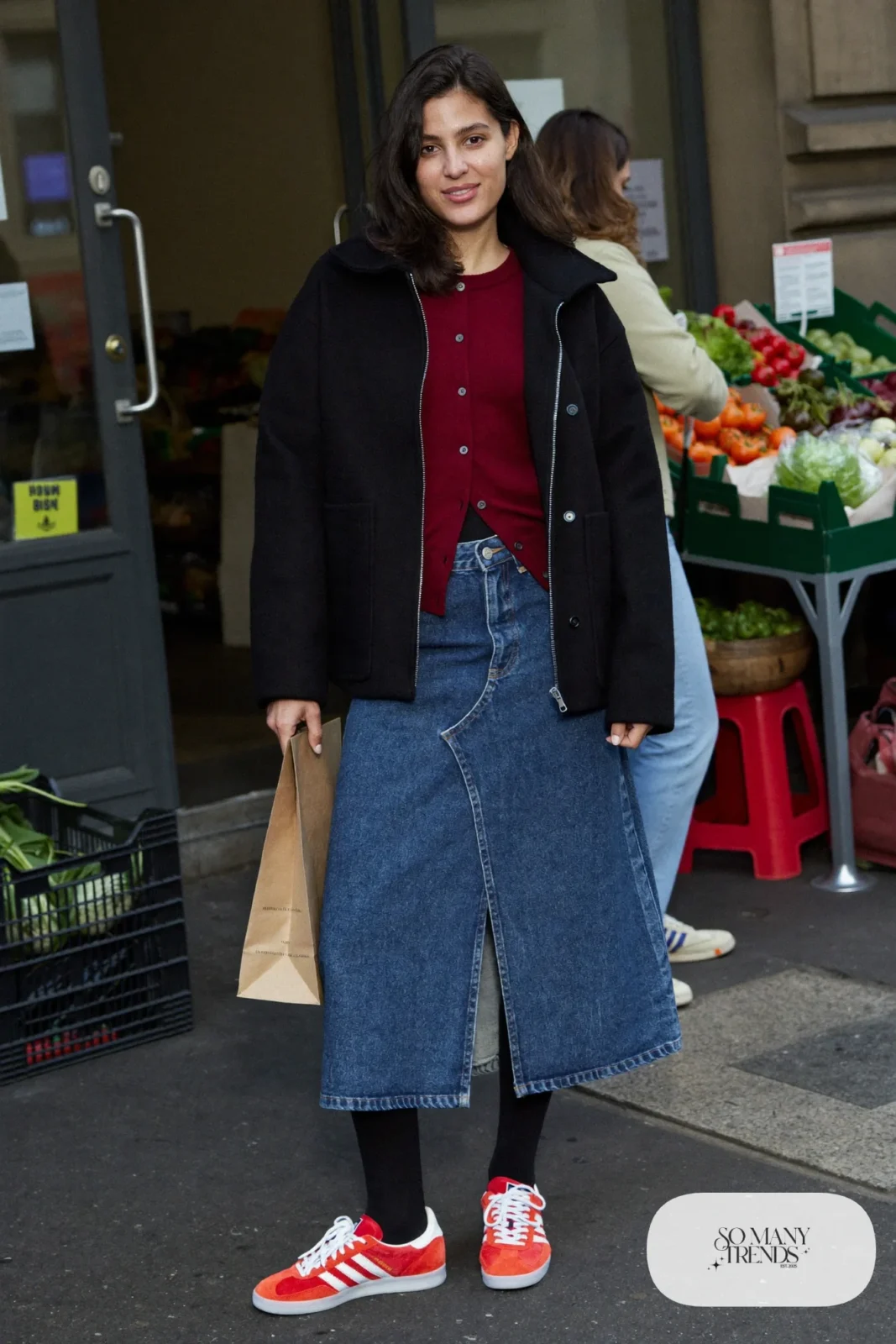 Woman in a mid-wash denim midi skirt, burgundy cardigan, black tights and red Adidas Gazelle sneakers, outfit 18