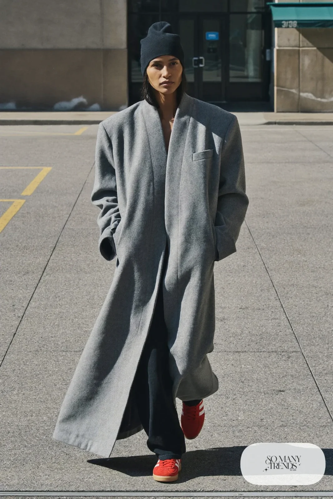 Woman in a long gray wool coat, black beanie, black pants and red Adidas Gazelle sneakers, outfit 19