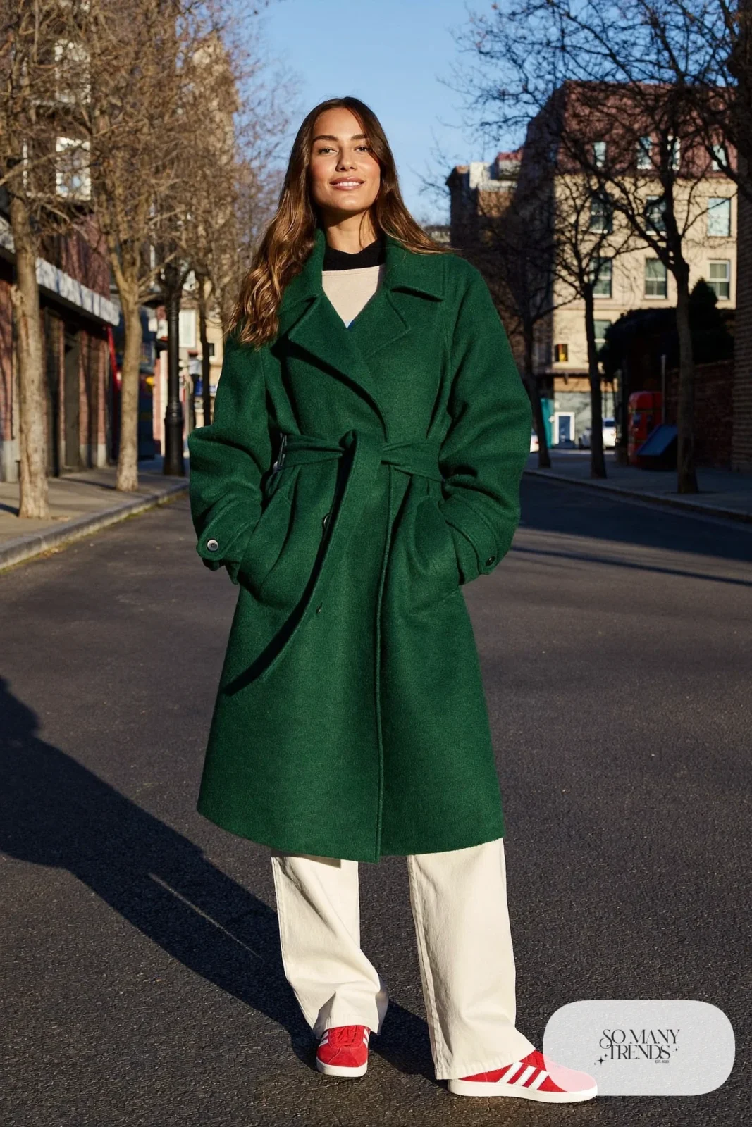 Woman in a forest green trench coat, cream wide-leg pants, black knit and red Adidas Gazelle sneakers, outfit 20