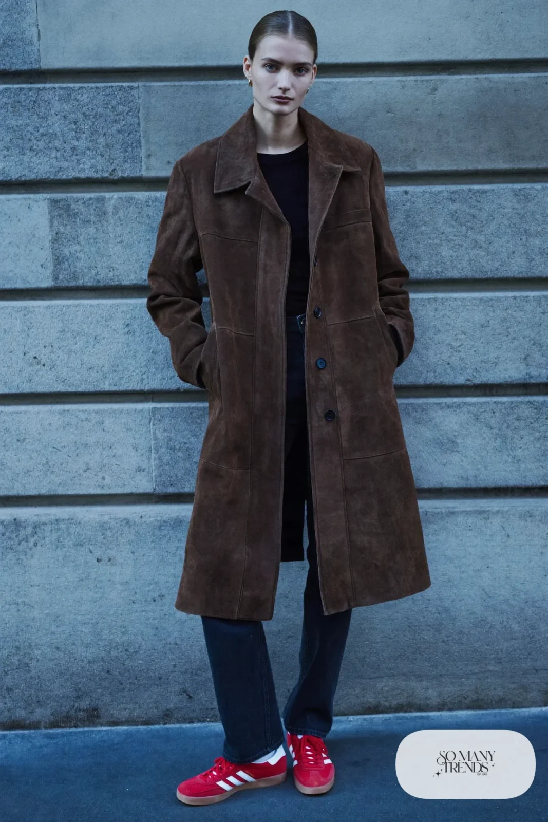 Woman in a chocolate suede coat, black knit top, black jeans and red Adidas Gazelle sneakers, outfit 23