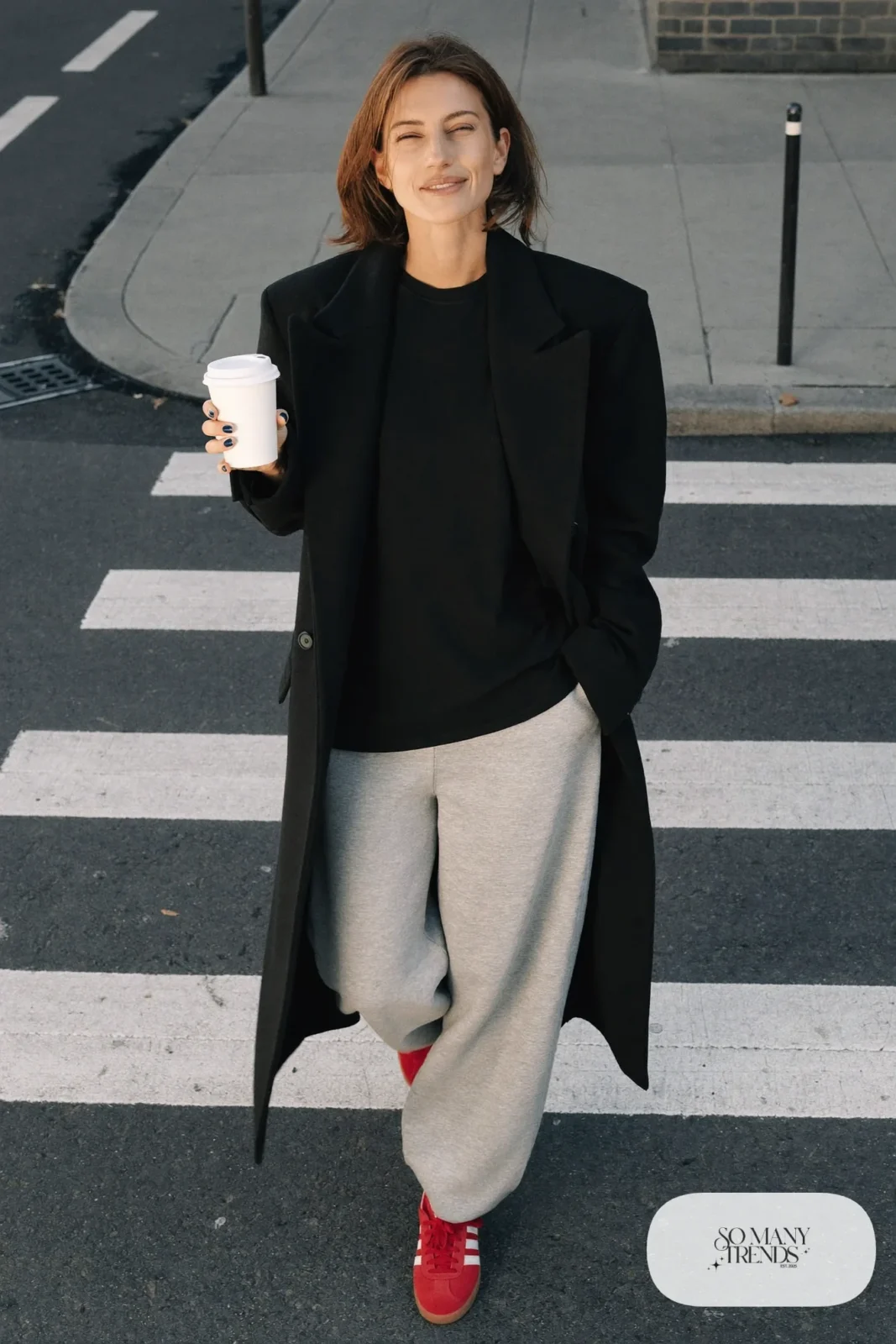 Woman in a black overcoat, gray straight-leg sweatpants, black tee and red Adidas Gazelle sneakers, outfit 25