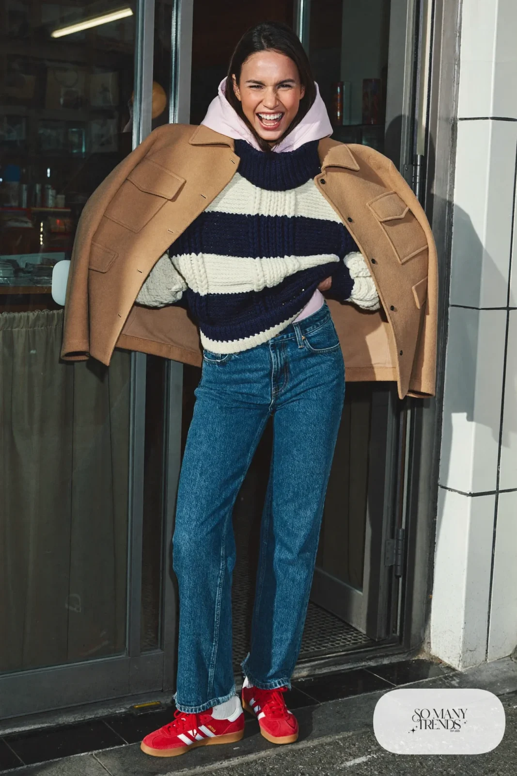 Woman in a navy and cream striped sweater over a pink hoodie, straight blue jeans and red Adidas Gazelle sneakers, outfit 28