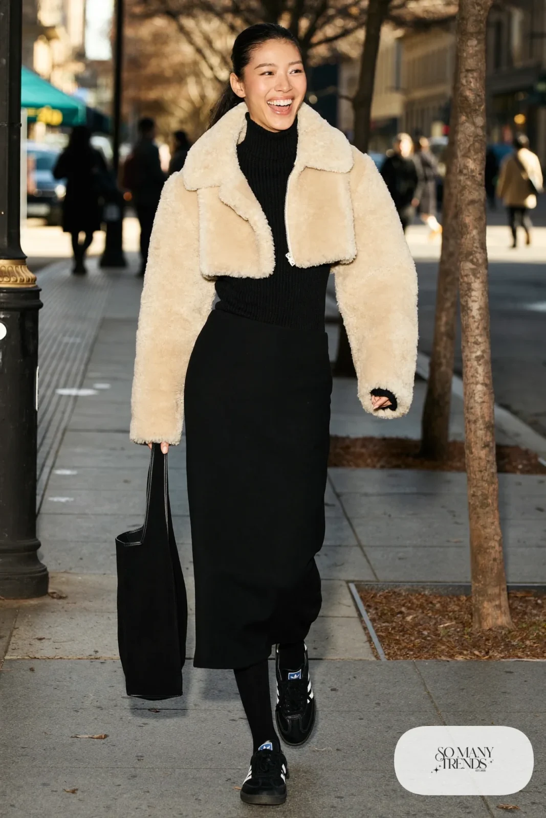 Woman in cropped cream shearling jacket, black wool midi skirt, black tights and black Adidas Campus sneakers, outfit 2