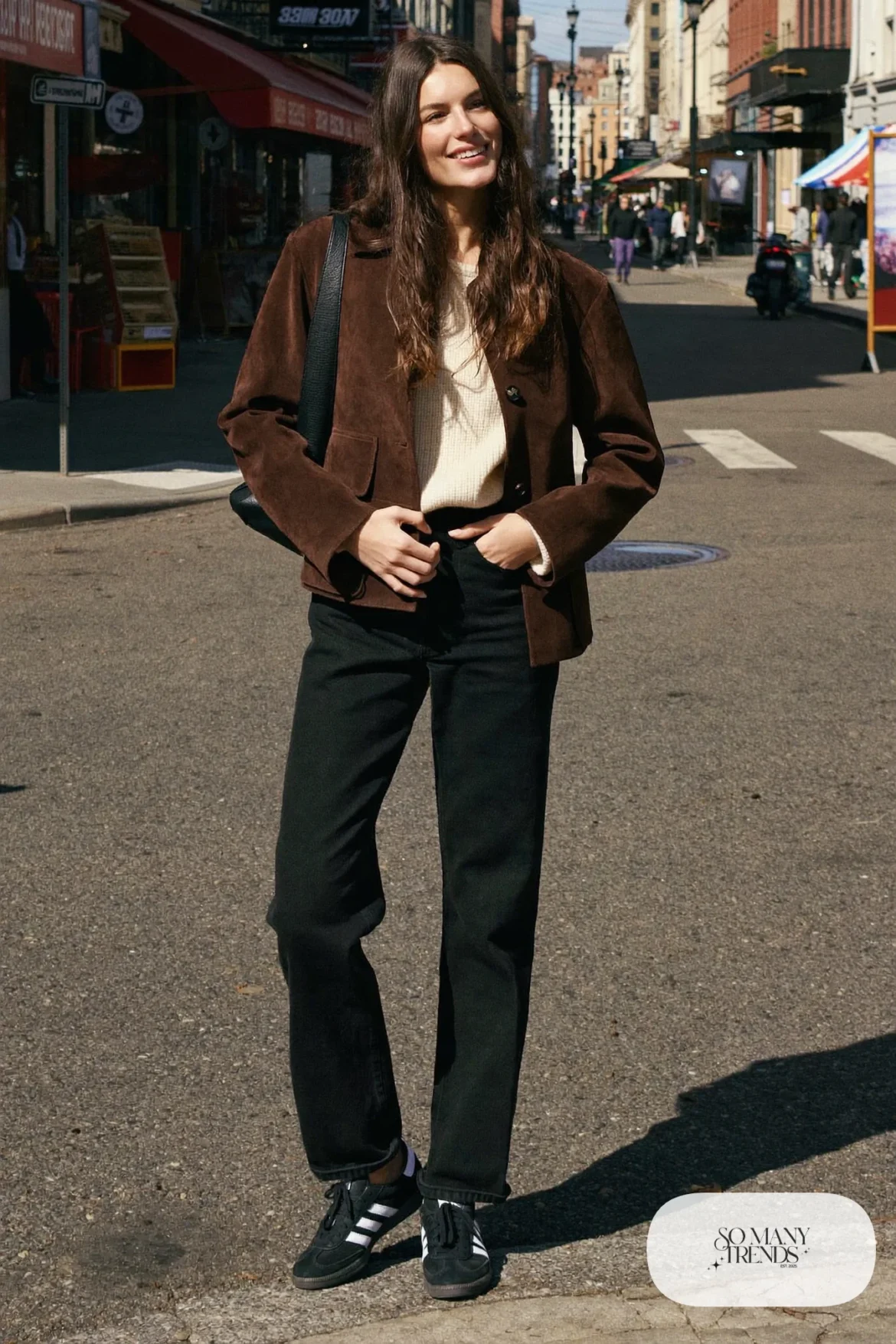 Woman in chocolate brown suede jacket, cream knit, black straight jeans and black Adidas Campus sneakers, outfit 8
