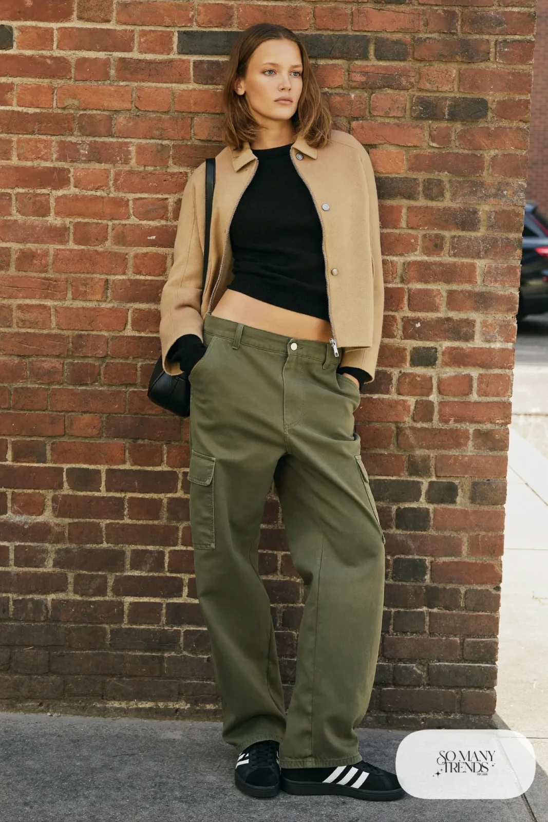 Woman in olive cargo pants, fitted black knit, short wool jacket and black Adidas Campus sneakers, outfit 13