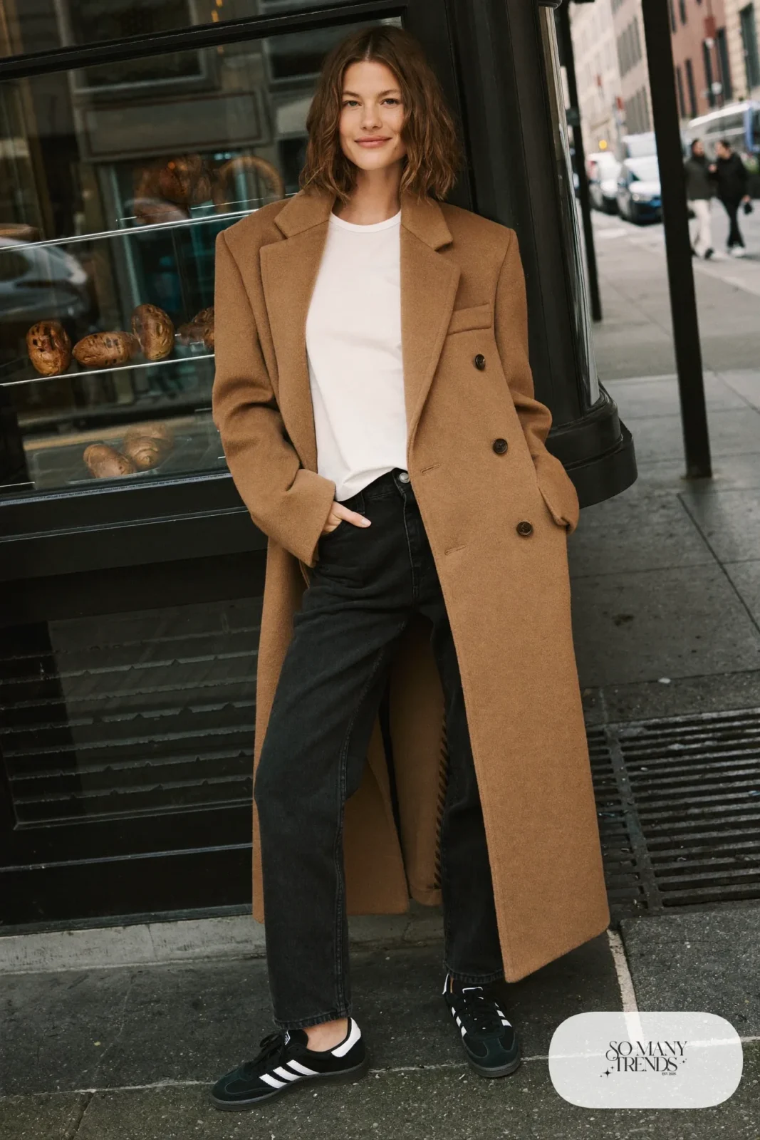 Woman in long camel wool cardigan coat, white tee, black jeans and black Adidas Campus sneakers, outfit 17