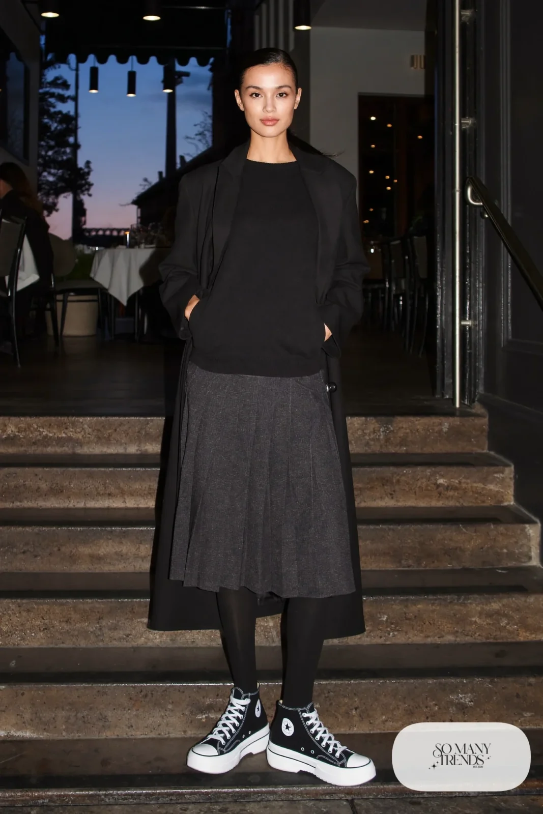 Woman in a long black tailored coat, pleated charcoal midi skirt, black tights and black Converse Run Star Hike platform sneakers - outfit 9