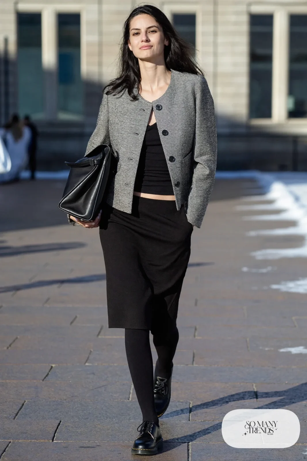 Woman in gray tweed boxy jacket, black knee-length skirt, sheer black tights and black Doc Martens loafers, outfit 6